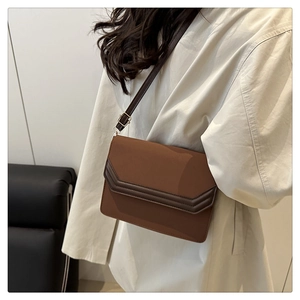 Détail du sac enveloppe en cuir PU marron avec coutures en V et finitions dorées