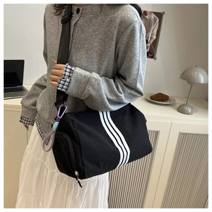Detail of black oxford dumpling bag featuring three side stripes and adjustable strap