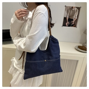 Detail of blue denim shoulder bag with brown braided rope strap and gold metal button