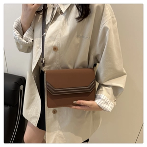 Détail d'un sac bandoulière en cuir marron avec rabat géométrique et finitions dorées