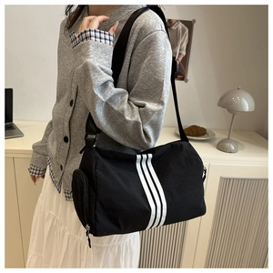 Detail of black cylindrical barrel bag with white stripes and side zip pocket