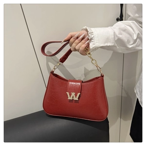 Dettaglio borsa rossa in pelle con logo W dorato, strass e tracolla a catena metallica
