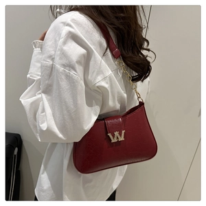 Dettaglio borsa sottobraccio vintage rossa con logo W dorato e tracolla a catena