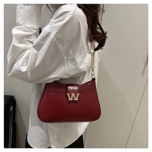 Dettaglio borsa sottobraccio rossa in pelle con fibbia a W dorata e catena in metallo