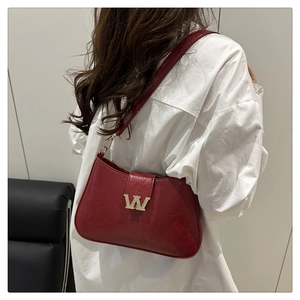 Dettaglio di borsa a spalla in pelle cerata rossa vintage con logo in strass dorati