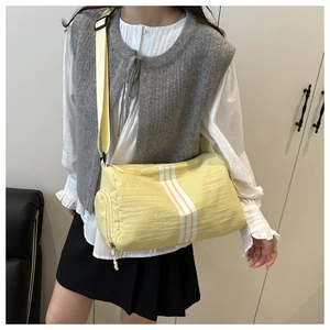 Detailed shot of yellow barrel crossbody bag with three white stripes and fabric strap