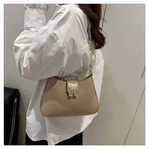 Dettaglio borsa a sella beige con fibbia a W dorata e tracolla a catena in oro