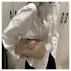 Dettaglio borsa a mezzaluna beige con fibbia a W dorata e tracolla a catena sul modello
