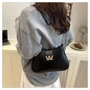 Dettaglio ravvicinato di borsa hobo nera testurizzata con logo W dorato metallico