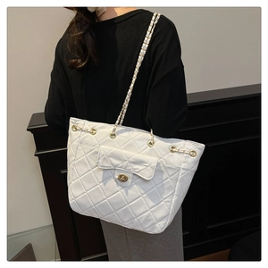 Détail du sac cabas matelassé blanc avec bandoulière chaîne dorée et finition texturée