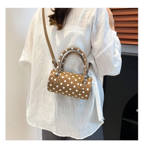 Detailed view of a brown polka dot mini cylinder bag with top handles and shoulder strap