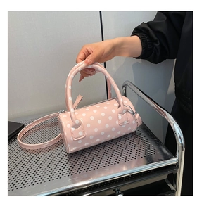 Detailed close-up of pink polka dot barrel bag showing glossy texture and strap