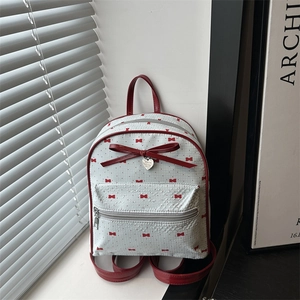 Mini white backpack with red bow print and heart charm for casual travel use