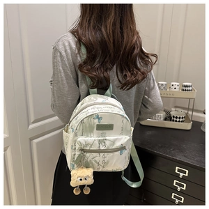 Detail view of mini backpack with Chinese calligraphy, butterfly pattern, and plush charm