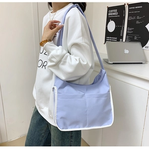 Détail du sac bandoulière en toile lilas avec bordure blanche et doubles poches avant