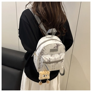 Detailed view of mini floral backpack with calligraphy print and plush charm on model