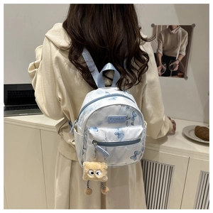Close-up of light blue butterfly print mini backpack with a plush charm on a model