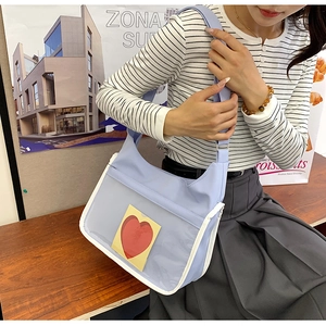 Detail of light blue shoulder bag featuring transparent pocket with red heart card
