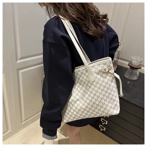 Detail view of cream tote bag with dark grey M-pattern monogram on shoulder