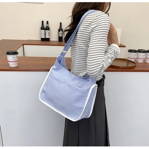 Detail of lavender nylon crossbody bag with white piping and dual large front pockets