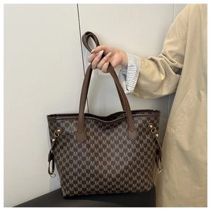 Close-up of brown tote bag with M-letter pattern and elegant leather handles