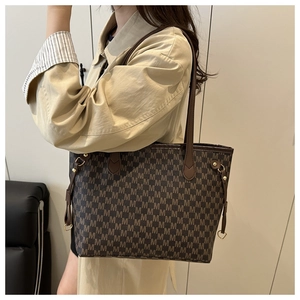 Detail of classic brown monogram tote bag with leather handles and gold metal hardware