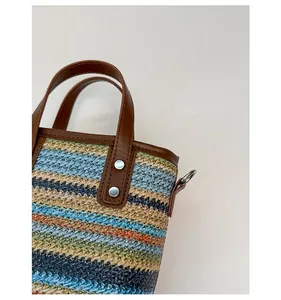 Détail du sac en paille tressée multicolore avec poignée renforcée en similicuir et rivets inox