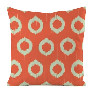 Close-up of bright orange faux silk pillow cover with green ikat circular patterns