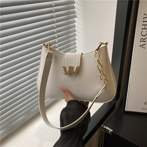 Borsa a mezzaluna bianca con emblema W dorato e tracolla a catena in una stanza