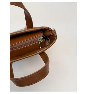 Détail du sac seau marron montrant la fermeture éclair argentée et la doublure interne
