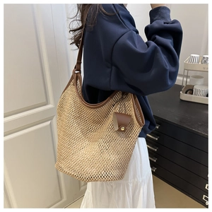 Detail of hand-woven large tote straw bag with elegant dark brown leather shoulder straps