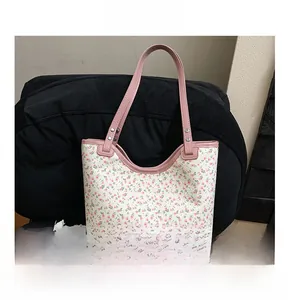 Detail shot of white floral tote bag with pink trim on a black textured chair