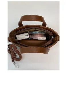 Détail de l'intérieur d'un sac seau en cuir marron montrant la capacité et la bandoulière