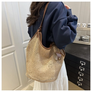 Close-up of woven straw texture and brown leather strap on a large summer tote bag