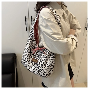 Close-up of leopard print tote bag with brown leather label and red ribbon details
