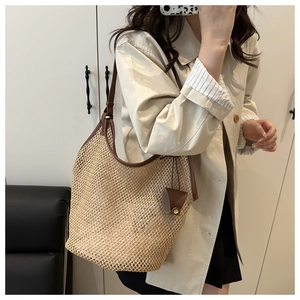 Detail of beige mesh woven beach tote with brown leather handles and mini bag charm