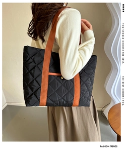 Quilted tote bag detail with orange webbing strap on a model in a minimalist room