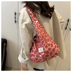 Detail of red leopard print fabric tote bag with white woven label on model's shoulder