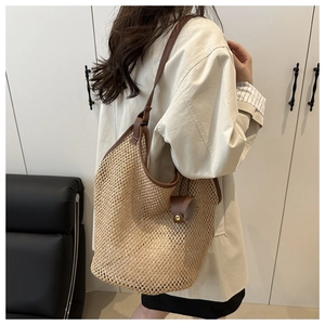 Detail of hand-woven straw tote with brown leather trim and metallic rivets detail