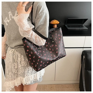 Shoulder view of large black cherry print tote bag on model for casual daily outfit