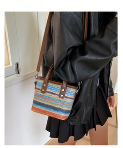 Vue détaillée du sac seau tissé à rayures colorées avec des lanières en cuir marron