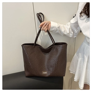 Gros plan d'un sac cabas tissé marron foncé avec texture cuir et plaque Fashion
