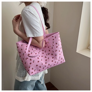 Detail of pink floral tote bag with cherry print shown on shoulder for size