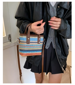 Detailed close-up of a striped woven tote bag with brown leather handles and hardware