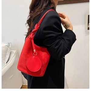 Detail of red suede bucket bag showing bold knotted handle and circular coin purse charm