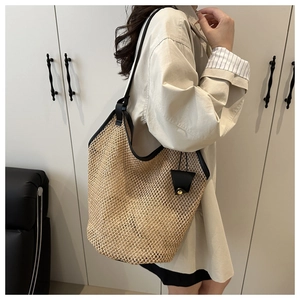 Detail of a large straw tote bag with black trim and small decorative side pouch