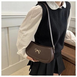 Close-up of a deep coffee leather underarm bag featuring a gold bow metallic buckle