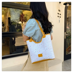 Outdoor shot of a large floral canvas tote bag with yellow leather trim and colorful dots