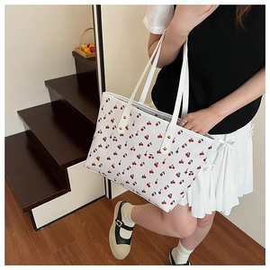 Détail du sac cabas blanc avec imprimé cerises et rivets dorés sur les poignées de sac