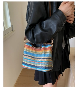 Détail du sac seau en paille arc-en-ciel avec poignées en cuir et boucle métallique